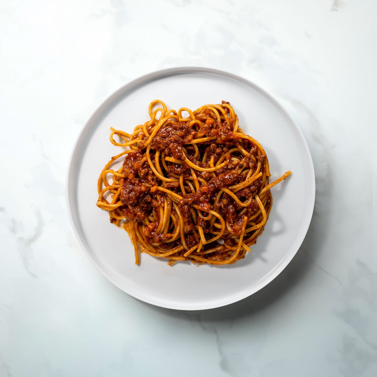 Teller mit langen Nudeln und Bolognese Wagyu Nero auf Marmor