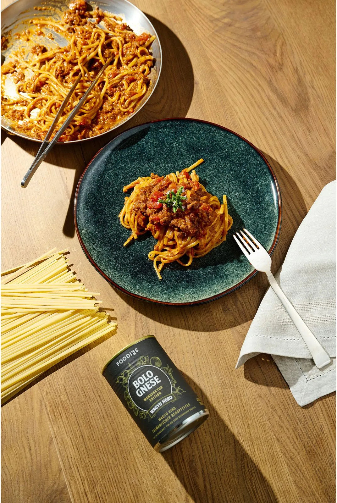 Tagliolini mit Wagyu Nero Bolognese auf dem Teller, daneben die Dose Wagyu Nero